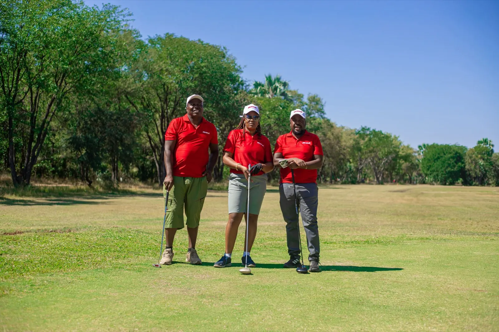 Three golfers in red shirts on the fairway at the ZAPF golf day
