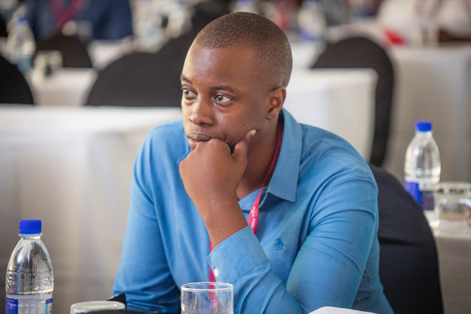 A delegate in a blue shirt listens closely during a conference session